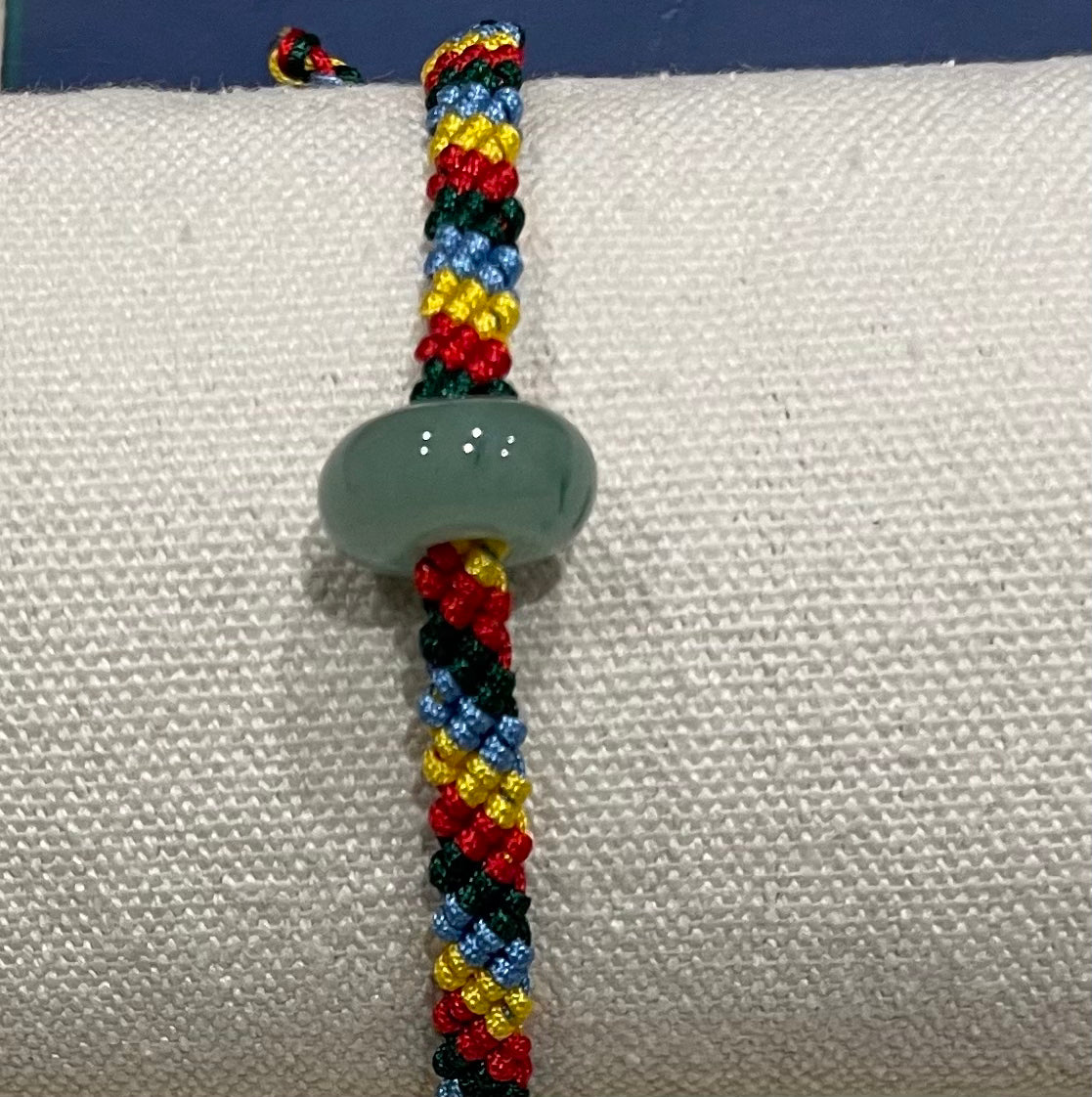 Handmade bracelet with colourful string and a jade ring